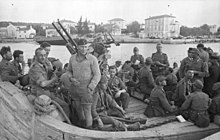 Des soldats sur un bateau, traversant un fleuve.