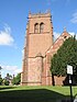 A sandstone church with the embattled tower on the left, and the body of the church on the right, seen end-on