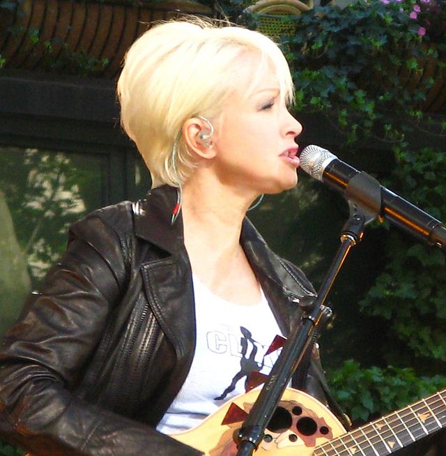 Cyndi Lauper playing a guitar.