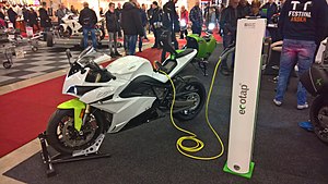 white racing-style motorcycle with electric hook-up cable in an exhibition hall