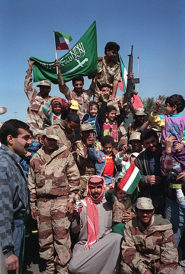 Civilians and coalition military forces wave Kuwaiti and Saudi Arabian flags as they celebrate the reversal of the annexation of Kuwait by Iraq (28 Fe