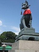 Inari-kitsune fox in front of an Inari shrine with a key in its mouth.jpg