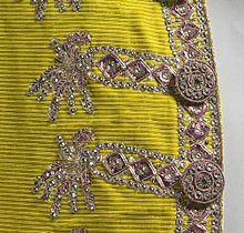 Paljettikirjontaa raidalliseksi kudotulle keltaiselle silkille. Miehen puvun rinnus 1700-luvun lopulta.