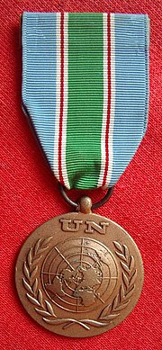 Advers av FN-medaljen for UNIFIL i Libanon. Medaljen har FNs emblem, mens båndet har FNs lyse blå farge, sammen med rødt, hvitt og grønt, farger fra Libanons flagg. Foto: Rémi Stosskopf