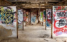 The interior of one of the farm's buildings in 2016. The partitions have been painted with graffiti. NYC Farm Colony 2016.jpg