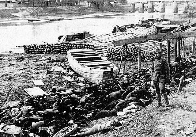 A Japanese soldier pictured with the corpses of Chinese civilians by the Qinhuai River
