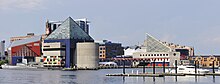 Left to right: The red building with a green glass front (north) wall holds the 2005 extension, the blue building with the glass pyramid top is the main building of poured concrete construction from 1981, and behind it,  across a pedestrian bridge to the east is the Pier 4 marine mammal pavilion.