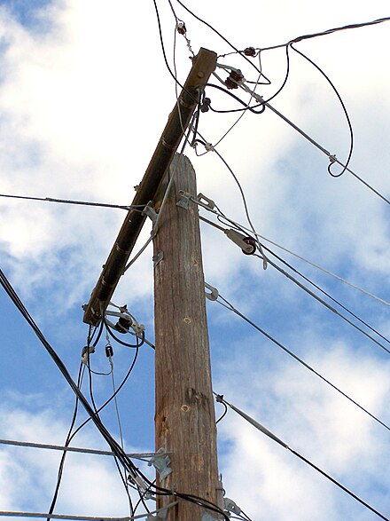 Utility pole with electric lines (top) and telephone cables.