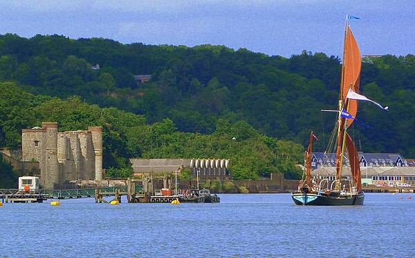 A Thames Barge sails past the depot: Upnor Castle (left), 'B' Magazine (centre), No. 5 Shell Store (right).