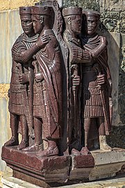 A sculpture depicting four armed men embracing each other in pairs