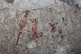 Peinture représentant une scène d'initiation, mithréum de Santa Maria Capua Vetere, deuxième quart du IIIe siècle. Le néophyte est au centre, nu, mains liées et à genoux, maintenu par le guide vêtu de blanc à gauche, et le Pater à droite en rouge, en grande partie effacé.