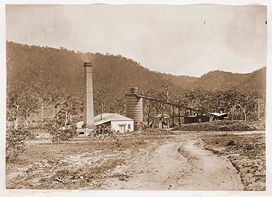 Original blast furnace (1875-1882) with its engine house on the left, taken in 1877. The inclined structure provided access to the furnace top for charging the furnace. Engine house and blast furnace, Esk Bank iron works, 1877 (8287083336).jpg