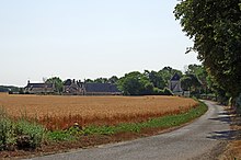Photographie en couleurs d'un hameau traversé par une route.