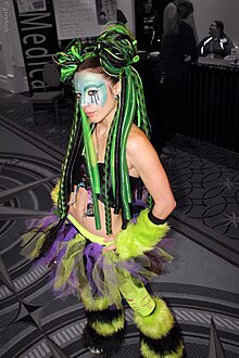 A girl in a cyber outfit wearing green and black furry leg warmers Girl in cyber costume at Katsucon 2013.jpg