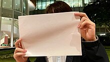 A blank piece of A4 paper, held up in protest by a student at Hong Kong University HKU student white paper protest 20221129.jpg