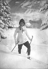 Photographie en noir et blanc d'une femme seule à skis dans un décor enneigé.