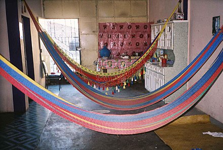 Three Salvadoran synthetic-thread hammocks (hamacas) strung inside a living room in Morazán Department, El Salvador.