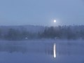 Moonlight illuminates a lake and surroundings.