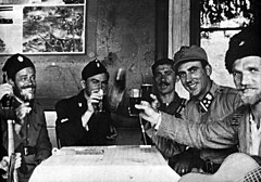bir masanın etrafında oturan üniformalı erkeklerin siyah beyaz fotoğrafı, birkaçının elinde gözlük