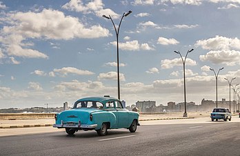 Chevrolet sedã de 1950 na avenida Malecón, Havana, Cuba. Malecón (oficialmente Avenida Maceo) é um amplo passeio, estrada e quebra-mar que se estende por 8 km ao longo da costa, da foz do porto de Havana em Havana Velha, ao longo do lado norte do bairro Centro Habana e do bairro Vedado, terminando na foz do rio Almendares. Novos negócios estão surgindo no passeio devido às reformas econômicas em Cuba que agora permitem que os cubanos tenham negócios privados. A construção da Malecón começou em 1901, durante o regime militar temporário dos Estados Unidos. O principal objetivo de sua construção era proteger Havana do mar. (definição 4 719 × 3 066)