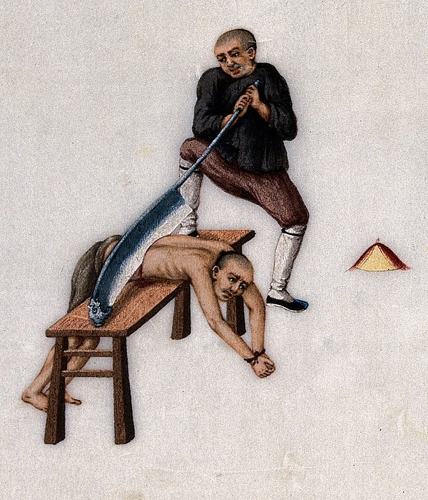 A prisoner is executed on a wooden bench with a large blade.