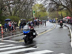 Lead men just past mile 19, with Gabriel Geay (at left) well ahead of the pack. For a closer view of the pack seconds later, see this photo. Geay leading the men BM2023.agr.jpg