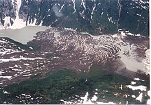 Brown rock lying in a glaciated valley with a small lake on the left.