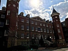 Color image looking up at red, brick building with staircase before the entrance and in between two towers