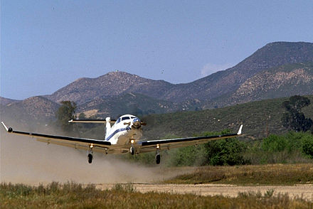 Pilatus PC-12 taking off from a short, unpaved airstrip