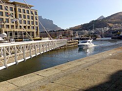 An example of how small swing bridges like this one may be pivoted only at one end, but that does require substantial underground structure to support the pivot. Victoria & Alfred Waterfront, Cape Town. Swing Bridge and ferry in motion.jpg