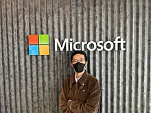 รูปภาพแสดงนายธนกร โชตยะกฤต กอดอกหน้าป้าย Microsoft