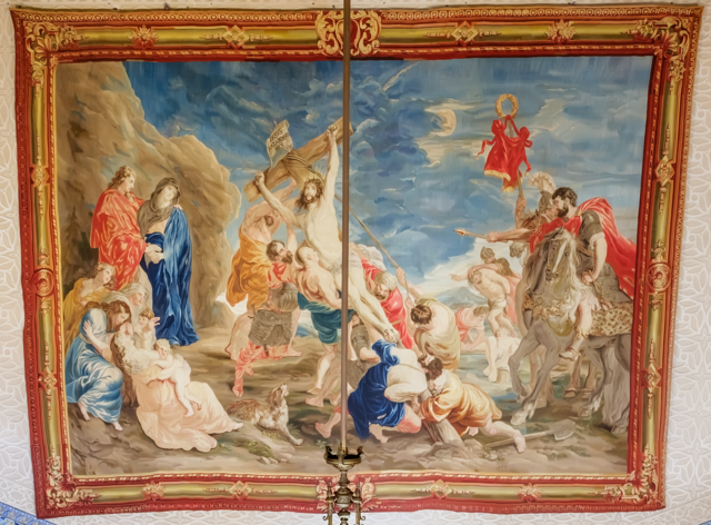 Photograph of an antique tapestry reproducing Rubens' triptych 'The Elevation of the Cross'. Woven by Jean-Baptiste Vermillion in the 18th century, the tapestry displays detailed biblical scenes enriched with vibrant colors. It is located in the Episcopal Palace of Segovia.
