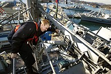 Worker secured by a lifeline. US Navy 051220-N-9389D-092 Quartermaster Seaman Matthew Lenerville, secures a safety line on railing while working aloft to hang holiday lights on the mast aboard the conventionally-powered aircraft carrier USS Kitty Hawk (CV 6.jpg