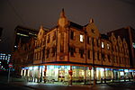 Built on the site of the Old Post Office Bar, adjacent the Law Chamber Building. It was designed by Frans Soff being built in 1902. Anton van Wouw did the sculpture work. The ground floor had the Cafe Riche Lounge Bar. Cafe Riche night.JPG
