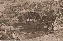 Artilerii în jurul unui tun răsturnat într-o vale.