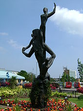 Bronze sculpture in the form of a mother with her children growing from the earth and reaching to the sky. A representation of the town's Latin motto; Ex terra vis. The sculpture is surrounded by colourful flower beds
