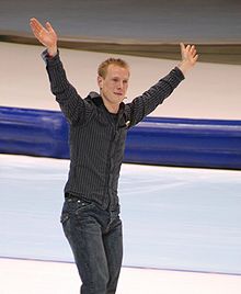 Jochem Uytdehaage sur la glace, les mains levées, il est habillé en street, pas en compétition, en vêtements.