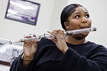 Lizzo plays a crystal flute from US President James Madison at the Library of Congress in 2022 Lizzo plays Madison flute (52391368441).jpg
