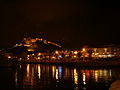 Escena nocturna del puerto, con el Castillo de Santa Bárbara al fondo.