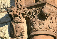 Close-up view of details on the building show a carved gargoyle hanging off the top of a column.