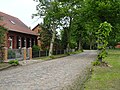 Dorfstraße mit Kopfsteinpflaster, Gehwegen und Baumbestand