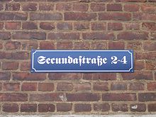 Straßenschild Secundastraße, benannt nach der Ehrenbürgerin, Schwester Maria Secunda, die von 1909 bis zu ihrem Tod 1957 im Kloster Maria Hilf als Ordensschwester tätig war.[25]