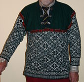 Lusekofteliknande genser med strikka selbumønster og metallspenner i halssplitten.