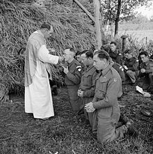 A priest administers Communion during Mass in a Dutch field on the front line in October 1944.
