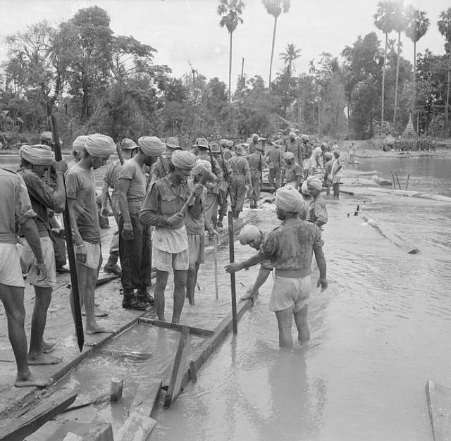 Indian engineers construct a wooden bridge during the advance to Rangoon, Burma Campaign.