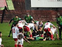 Des joueurs de rugby autour d'un regroupement au sol, à un mètre de la ligne d'en-but.