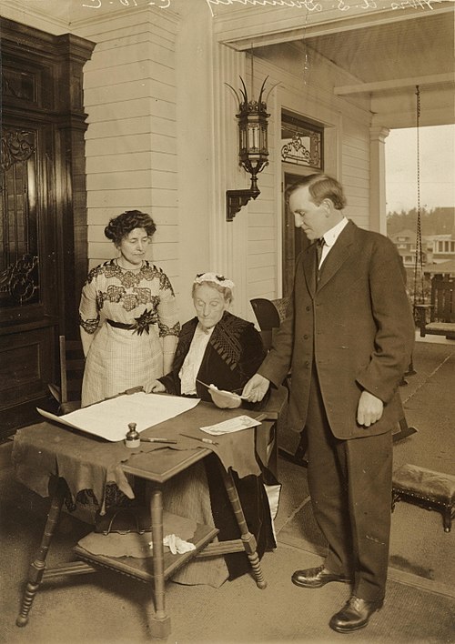 Abigail Scott Duniway (seated) with Governor Oswald West, signing the women's suffrage amendment