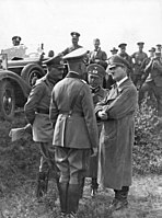 "Zleva: Werner von Blomberg, generál Werner von Fritsch a říšský vůdce a kancléř Adolf Hitler v rozhovoru s neznámým generálem během podzimních manévrů u města Celle dne 7. září, 1935."