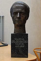 Bronze bust of Marie Curie, on green marble stand. Presented by the Polish Chemical Society to the Royal Institute of Chemistry on the latter's centenary in 1977. Now in the Royal Society of Chemistry's HQ at Burlington House, London. Gold lettering on the stand reads "Maria Sklodowska Curie 1867-1934". Burlington House - 2015-07-29 - Andy Mabbett - 18.JPG