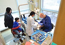 Stafford County residents watch a Germanna Community College dental hygiene student work on a patient during a free dental clinic sponsored by the school's dental program at the Moss Free Clinic in Fredericksburg, Virginia. Dental hygiene students help kids with free clinic (24255485193).jpg